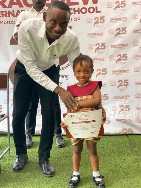 A teacher presenting an Academic Achievement Award to a young Gracedew pupil