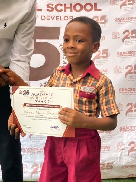 A Gracedew pupil holding an Academic Achievement Award certificate