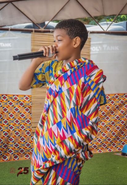 A Gracedew pupil singing into a microphone in kente on Cultural Day